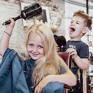 Zwei Kinder haben Spass im Friseursalon